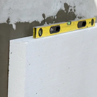 Amierungsmörtel - Isolierung der Fassadenwand mit Styroporplatten. Polystyrol-Isolierplatten mit Klebstoff. - Stock-Fotografie