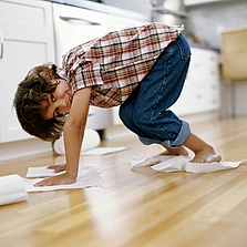 Hygienisch und extrem pflegeleicht - Boy (5-7) polishing floor with paper towel under hands and feet - Stock-Fotografie