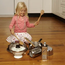 Schallschluckend - Girl (4-5) sitting in floor in kitchen, playing with kitchen utensils - Stock-Fotografie
